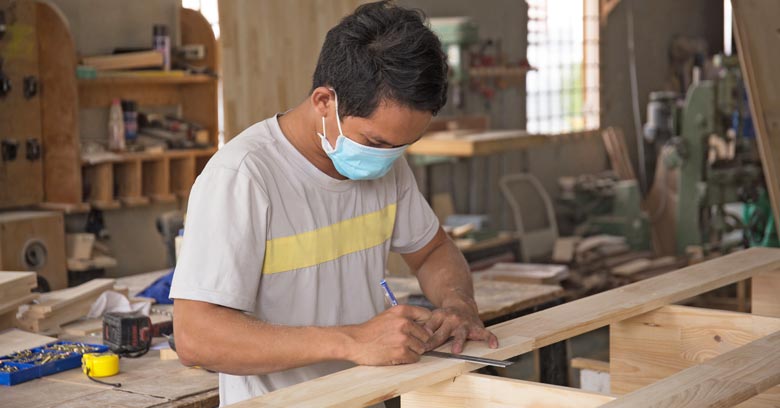 Vietnamese carpenter measuring wood for furniture