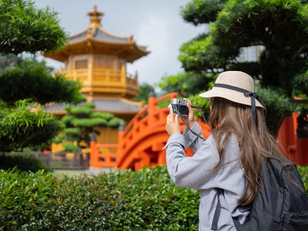 A tourist taking a photograph in a Chinese garden