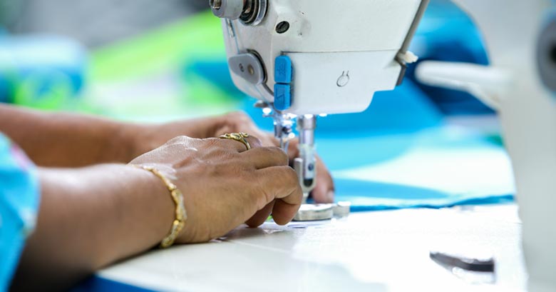 The hands of a Bangladesh textile worker using a sewing machine